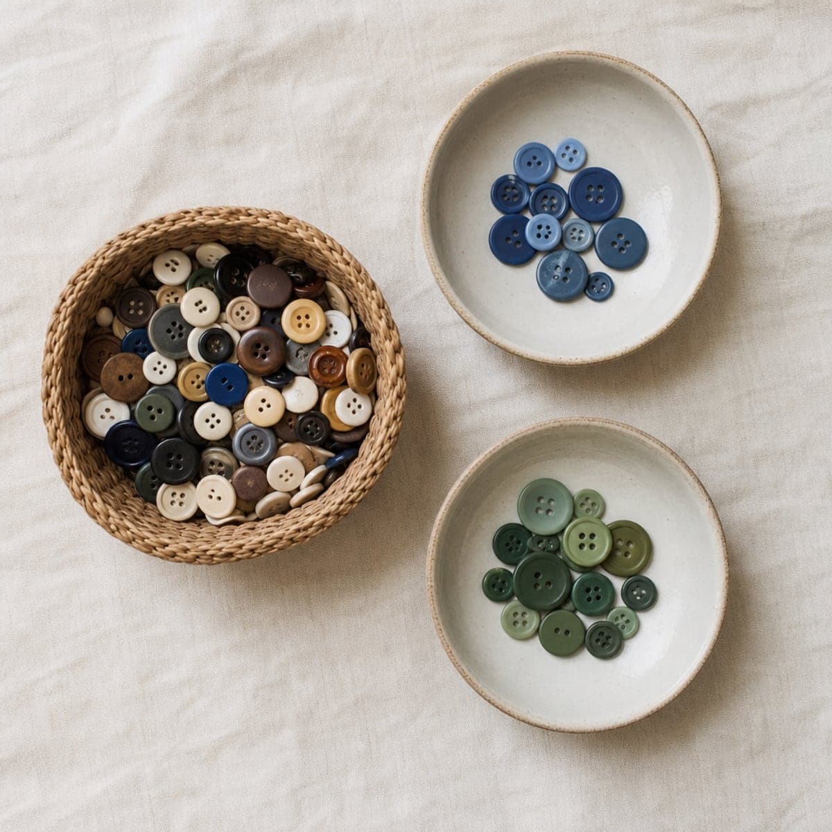A basket of mixed buttons beside two shallow bowls holding buttons sorted by colour